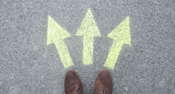 Man,Standing,On,Road,Near,Arrows,Marking,,Closeup