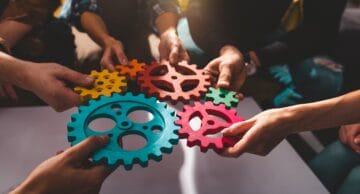 A group of hands each holding a wheel to indicate teamwork